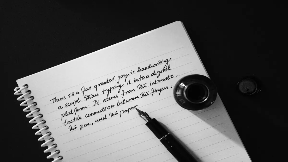 Fountain pen, ink bottle, and handwritten note on a spiral notebook against a dark background.