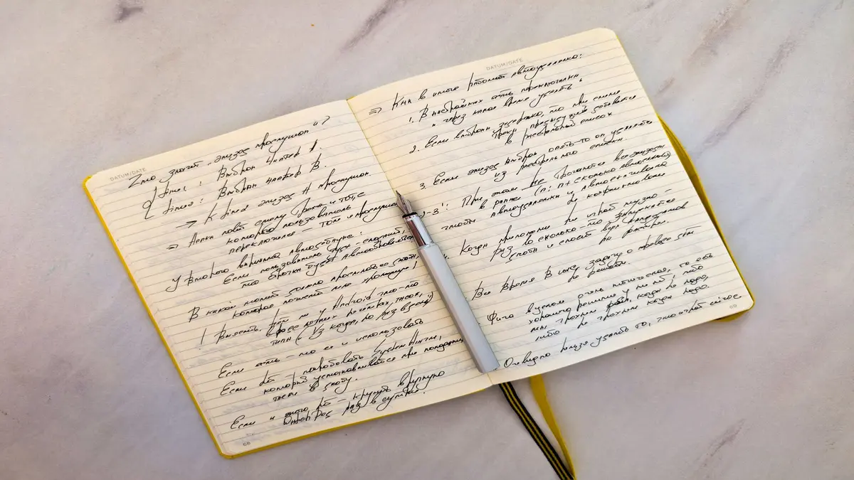 Open notebook with handwritten notes and a pen resting across the center pages.
