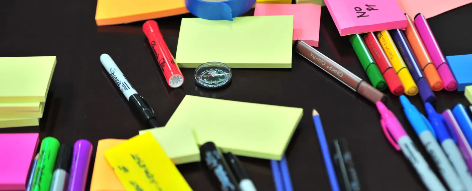 Colorful sticky notes, pens and markers spread across a table